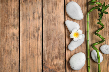 Flat lay composition with spa stones and space for text on wooden background
