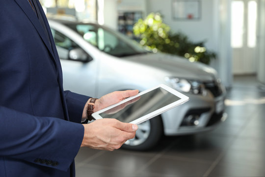 Young Car Salesman With Tablet In Dealership, Closeup