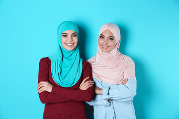 Portrait of young Muslim women in hijabs against color background