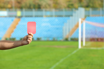 Football referee showing red card at stadium, closeup with space for text