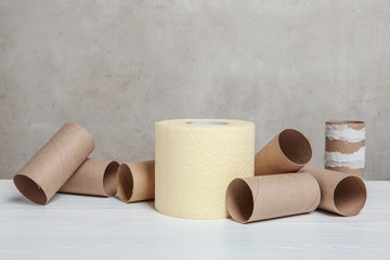 Full and empty toilet paper rolls on table against grey background. Space for text
