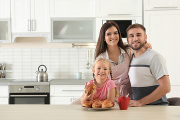 Happy family with freshly oven baked buns at table in kitchen. Space for text