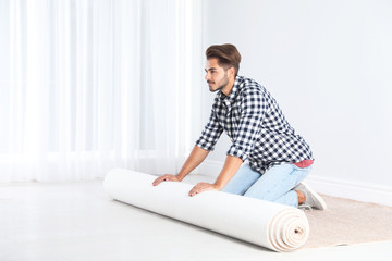 Man rolling out new carpet flooring indoors. Space for text