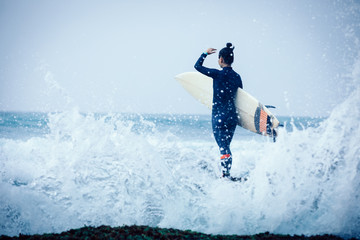 Woman surfer with surfboard going to surf the big waves