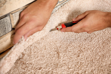 Man cutting new carpet flooring indoors, closeup