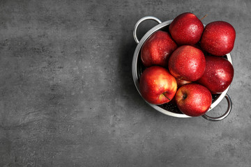 Juicy red apples in colander and space for text on grey background, top view