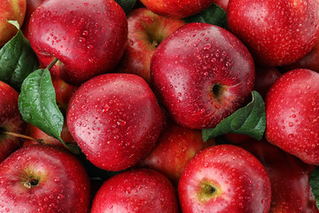 Viele reife saftige rote Äpfel, die mit Wassertropfen als Hintergrund bedeckt sind