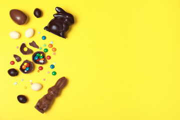 Flat lay composition with chocolate Easter eggs and space for text on color background