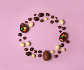 Flat lay composition with chocolate Easter eggs and space for text on color background