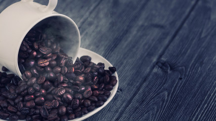 Roasted premium coffee bean in a white cup on black  and wooden background.