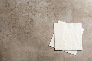 Clean paper napkins and space for text on grey background, top view - obrazy, fototapety, plakaty