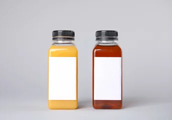 Fototapeten Tasty drinks in bottles with blank labels on color background. Mock up for design © New Africa