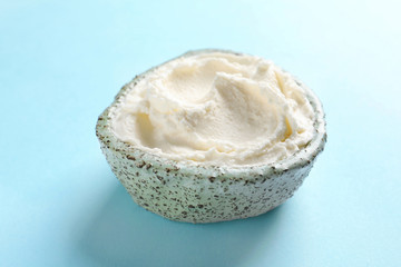 Bowl of tasty cream cheese on color background