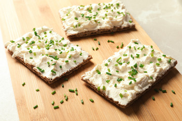 Tasty snack with cream cheese on wooden board
