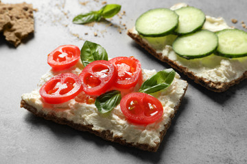 Tasty snacks with cream cheese and vegetables on gray table