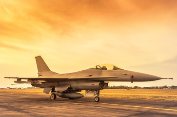 Fototapeta na wymiar Fighting military fighter jet aircraft parked on runway in the base airforce standby ready to take off for military mission on sunset