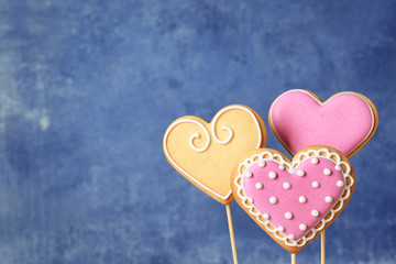 Fototapeta na wymiar Decorated heart shaped cookie pops on color background. Space for text