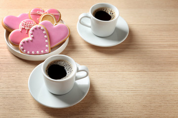 Romantic breakfast with heart shaped cookies and cups of coffee on wooden table, space for text