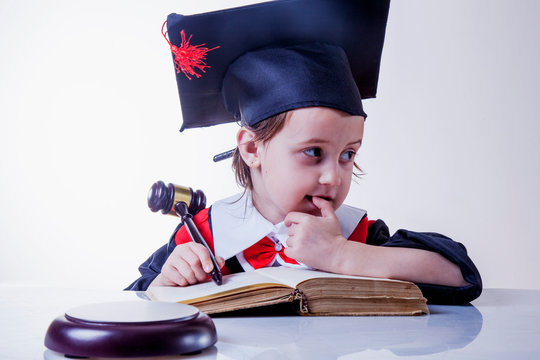 Portrait of serious child girl judge makes a decision. Humorous photo.(letter of law, strict law, justice concept)