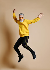 Fototapeta na wymiar Excited senior millionaire man dancing jumping in yellow sunglasses hands up fashionable men senior 