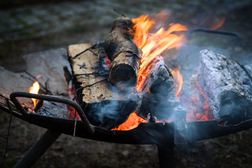iron fire bowl with burning wood logs warms up at open air events on cold nights, copy space