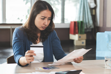 Asian woman calculating monthly expense and credit card debt.