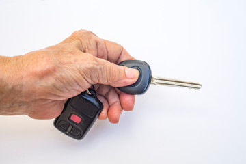 Senior woman's left hand holding car key with remote control isolated on white background