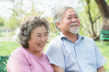 Asian healthy senior couple relaxing seated in the park together.