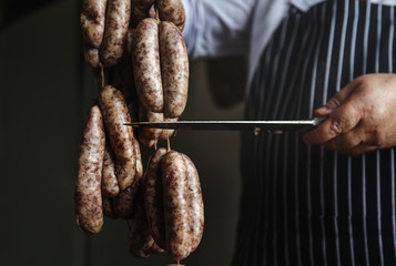 Butcher with smoked sausages on a string - obrazy, fototapety, plakaty