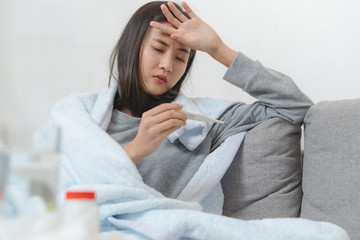 Woman measuring temperature her body on the bed. person got fever lying on the bed.