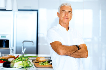Portrait of a smart senior man standing in kitchen
