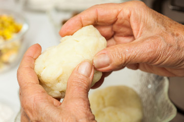 Preparation steps of traditional Colombian dish called stuffed potatoes: Kneading the mashed potatoes by hand to form a dough for the stuffed potatoes