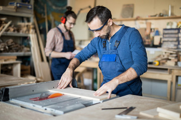 Portrait of mature carpenter working with wood in joinery, copy space