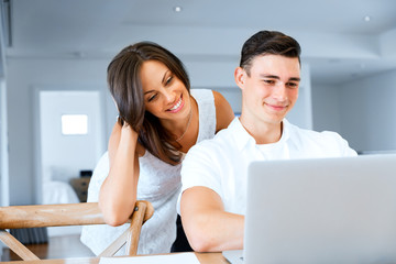 Happy modern couple working on laptop at home