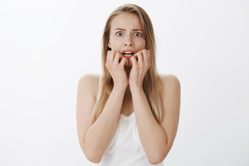 Girl scared for own life feeling terrified trembling, being frightened of spooky halloween costume. Shocked intense and horrified attractive woman with blond hair biting fingernails looking in camera