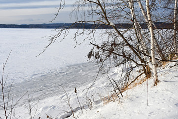 The shore of Vyazovy island and frozen lake Uvildy in Chelyabinsk region in winter in cloudy weather. Russia