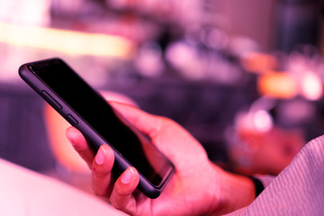 Woman hand using smartphone and laptop with cafe shop sunlight  shade to object beautiful background.