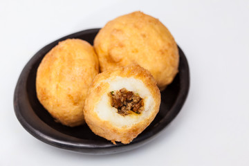 Preparation steps of traditional Colombian dish called stuffed potatoes : Ready stuffed potatoes served in a black ceramic dish isolated on white background