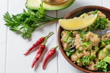 Salad of amaranth seeds, avocado, pepper, tomatoes, lemon and parsley with olive oil on a white light table. The view from the top.