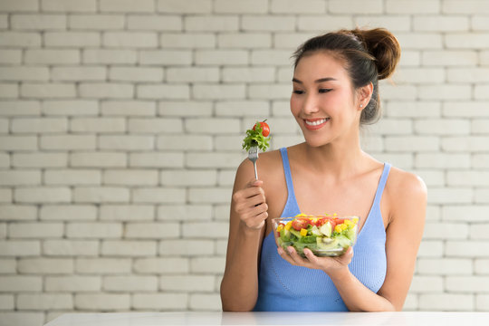 Asian woman in joyful postures with hand holding salad