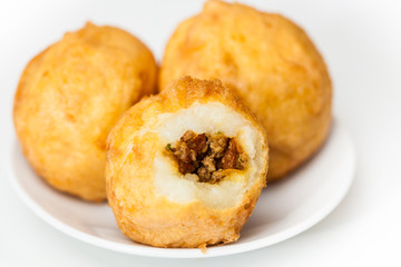 Preparation steps of traditional Colombian dish called stuffed potatoes : Ready stuffed potatoes served in a white ceramic dish isolated on white background