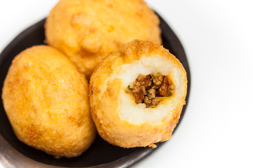 Preparation steps of traditional Colombian dish called stuffed potatoes : Ready stuffed potatoes served in a black ceramic dish isolated on white background