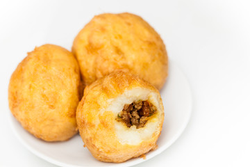 Preparation steps of traditional Colombian dish called stuffed potatoes : Ready stuffed potatoes served in a white ceramic dish isolated on white background