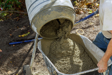 Worker uses a concrete made of in the concrete mixer at building construction works