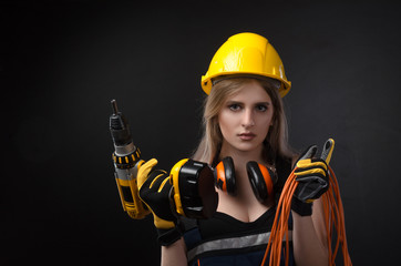 girl in construction clothes and protective equipment posing with a screwdriver