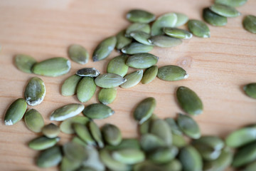 Dry pumpkin seeds scattered on a wooden background close up