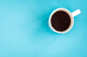 Coffee or black tea in white mug on blue background.