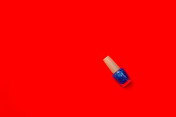 Bottle of nail polish on red background with copy space