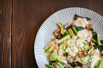 Close up Healthy salad with avocado , walnuts and grilled asparagus . Vegan food on dark wooden table.