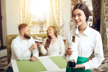 Beautiful girl waiter holds open bottle of wine